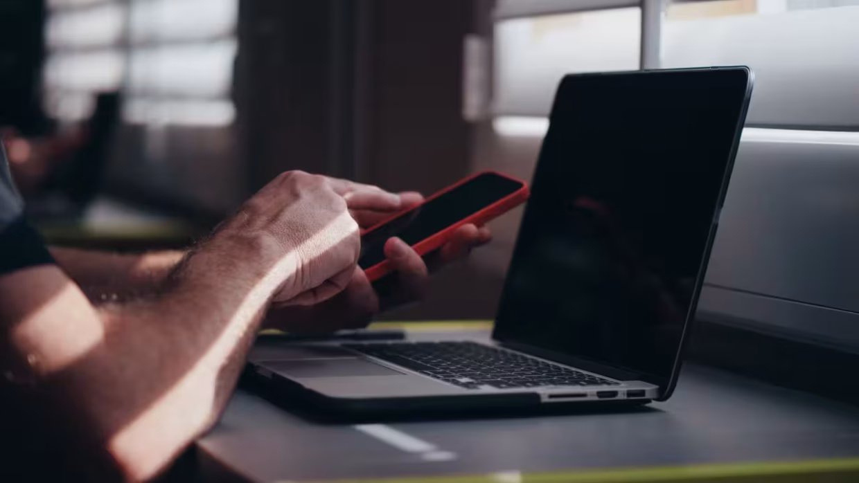 Hombre navegando la web en su móvil y en su portátil